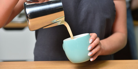 Barista girl makes coffee and pours it into a mug. Small business and addiction concept