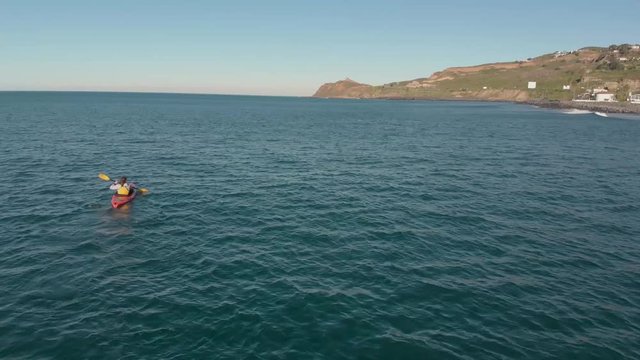 A surfer rowing a kayak in the ocean.