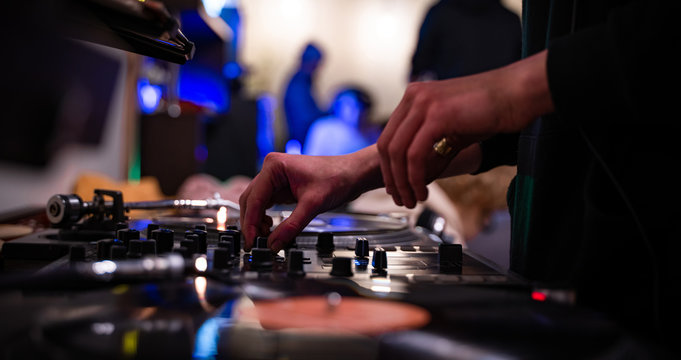 Female hip hop dj scratching vinyl records with music on party in night club.Professional disc jockey girl scratches old analog record with popular tracks.Concert audio equipment on stage. Moscow