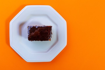 Carrot cake with chocolate topping isolated on orange background. Concept photo.