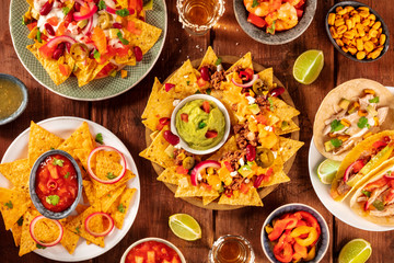 Mexican food variety, shot from the top on a rustic wooden background. Nachos, guacamole, tequila, tacos, a flat lay