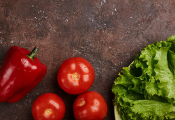 fresh veggies pepper tomatoes and lettuce on a plate on a brown background isolated