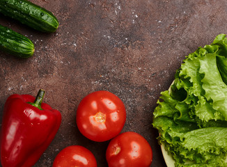 fresh veggies pepper tomatoes cucumbers and lettuce on a plate on a brown background isolated
