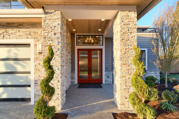 Modern home with stone and red door, glass garage door.