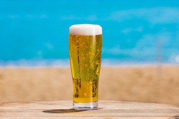 fresh beer with foam and the sea in the background