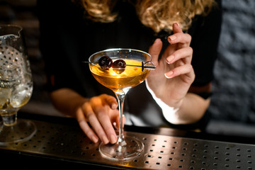 Close-up glass with ready-made cocktail accurate decorated berries by bartender