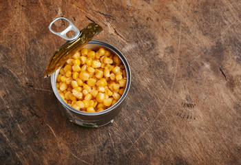 sweet corn grains in a tin open can on a wooden background