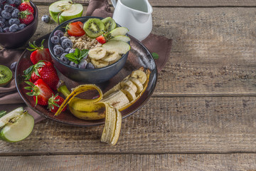 Breakfast oats. Morning oatmeal with various fruit and berries, on rustic wooden background copy space