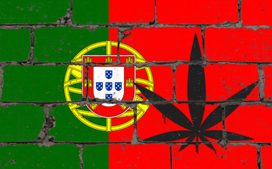 Graffiti street art spray drawing on stencil. Cannabis leaf on brick wall with flag Portugal