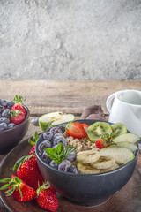 Breakfast oats. Morning oatmeal with various fruit and berries, on rustic wooden background copy space