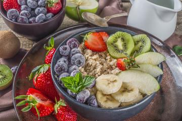 Breakfast oats. Morning oatmeal with various fruit and berries, on rustic wooden background copy space