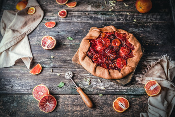 blood orange pie on wooden board with slices of oranges on wooden background