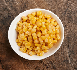 sweet corn grains in a white bowl on a wooden background