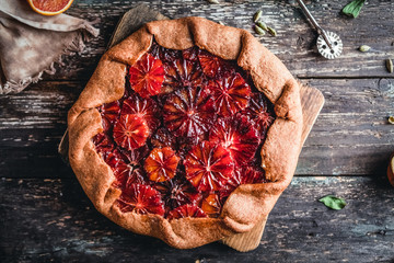 blood orange pie on wooden board with slices of oranges on wooden background