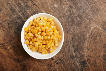 sweet corn grains in a white bowl on a wooden background