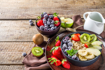 Breakfast oats. Morning oatmeal with various fruit and berries, on rustic wooden background copy space
