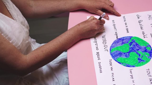 Woman draws world and writes all will be ok in many languages against coronavirus