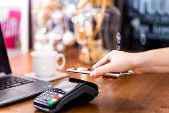 Woman using terminal for contactless payment via smartwatch for her coffee order in cafe. New technology of NFC payment. Cashless transaction