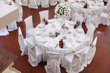 Wedding. Banquet. The chairs and round table for guests, served with cutlery, flowers and crockery and covered with a tablecloth