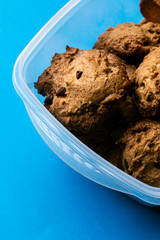 Homemade chocolate cookies biscuits on a plastic vase isolated on a blue background