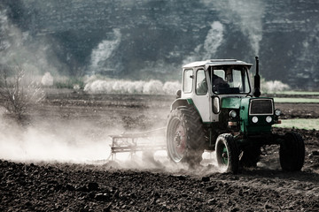 Farmer in tractor preparing land. Agricultural works at farmlands. agricultural work plowing land on a  tractor. Tractor on a farmer field in Moldova, Europe.
