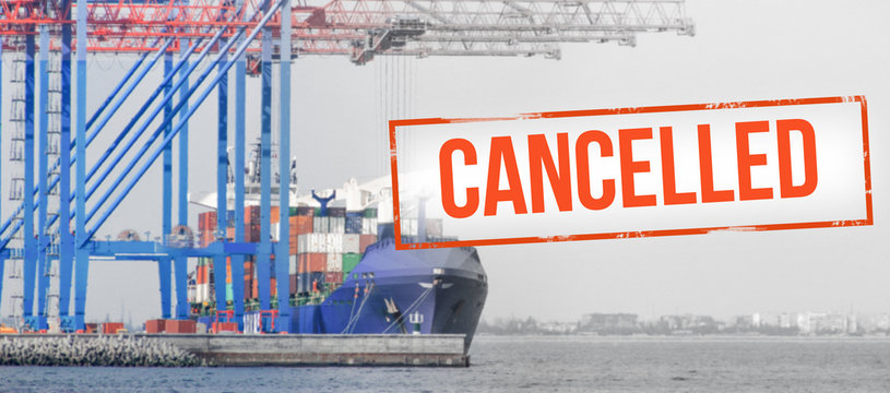 Red inscription "cancelled" on a blurred background of container ship  in cargo port. Concept: Global economic crisis, reduction of trade, suspension of carriage, halting production due to a pandemic