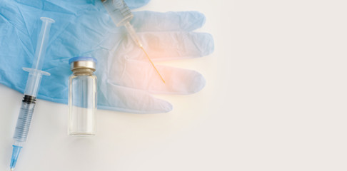 Banner with top view of medicine bottle, blue rubber gloves, syringes on grey background. Coronavirus vaccine development. 2019-nCoV liquid drug, virus antidote. Copy space. Health care concept.