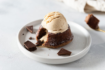 Delicious fresh fondant with hot chocolate centre and ice cream scoop on the plate. Lava cake recipe, menu. Close up