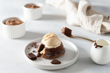 Chocolate lava cake with liquid centre and ice cream scoop on the top on white background. Restaurant menu, recipe. Side view