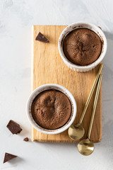 Chocolate lava cake with liquid centre in ceramic molds ramekins on wooden board on white...