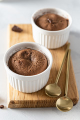 Chocolate lava cake with liquid centre in white ramekins on wooden board. Confectionery, cafe, restaurant menu, recipe, cookbook. Close up