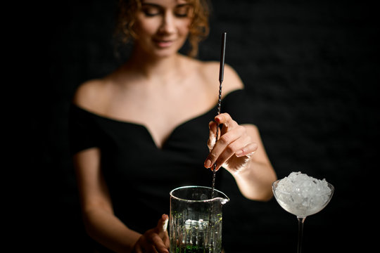 Close-up. Beauty young woman bartender mixed cocktail by long bar spoon.
