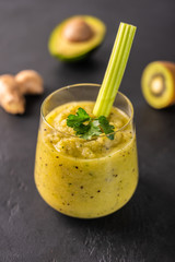 Freshly made green smoothie made of vegetables, fruits, herbs and greens on a dark background. Copy space