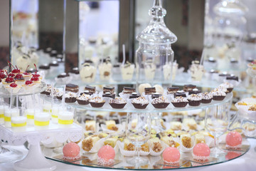 Close up of tray with lot delicious diversity pastry cakes tartlets and macaroon in a row. Fresh, multicoloured, colourful, green, yellow, white and pink sweet berry desserts, beautifully decorated