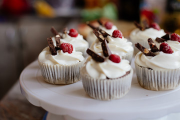 Chocolate cupcakes. Homemade chocolate muffins. The process of making homemade chocolate cupcakes with whipped cream and decorated with chocolate and raspberry pieces.