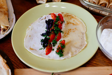 Homemade pancakes with different fillings. Pancake stuffed with soft cheese, tomatoes and basil.