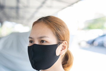 Asian woman wearing black fabric face mask. Concept of using medical mask to prevent the spread of...