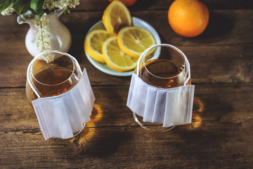 Glass goblets with alcohol. Medical protective mask. Citrus fruits. On a wooden table. Virus concept. Quarantine at home.