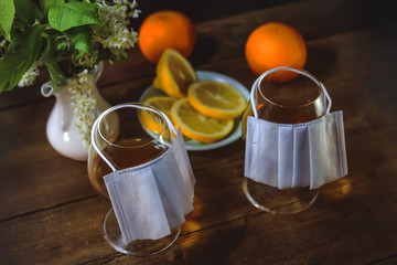 Glass goblets with alcohol. Medical protective mask. Citrus fruits. On a wooden table. Virus concept. Quarantine at home.
