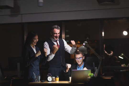 Group Of Diversity Business People Working Late In Office At Night. Two Caucasian Men And Asian Secretary Girl Feel Happy And Success. Working Late Night And Overtime Concept