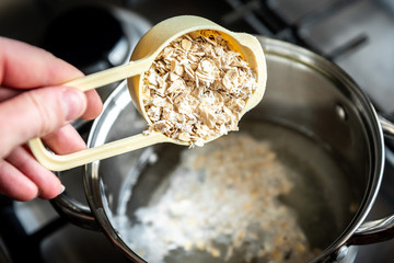 Cooking healthy oat porridge in metal pot.