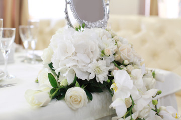 Wedding. Banquet. The chairs and round table for guests, served with cutlery, flowers and crockery and covered with a tablecloth