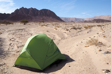 The light green tent and the far dark mountain in the desert, the blue sky with white clouds.