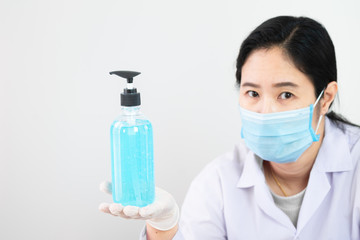 The bottle of alcohol sanitizer cleaner on hand of a nurse or doctor or physician assistant with selective focus