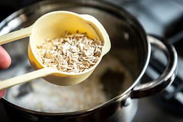 Cooking healthy oat porridge in metal pot.