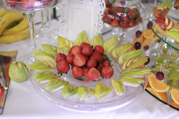 Close up of tray with lot delicious diversity pastry cakes tartlets and macaroon in a row. Fresh, multicoloured, colourful, green, yellow, white and pink sweet berry desserts, beautifully decorated