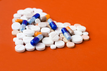 Heap of pills, tablets, capsules on red orange background. Drug prescription for treatment...