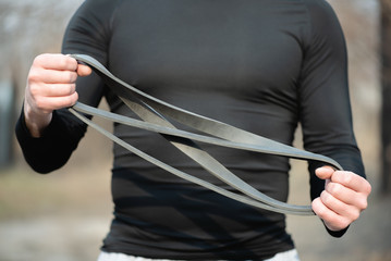 Man is training with band expander close up outdoor.