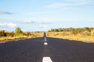 A straight asphalt road with meadows on both sides