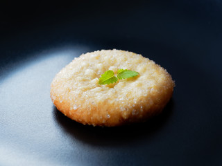 Appetizing sugar cookies on a black background. One cookie with lemon balm, top view.